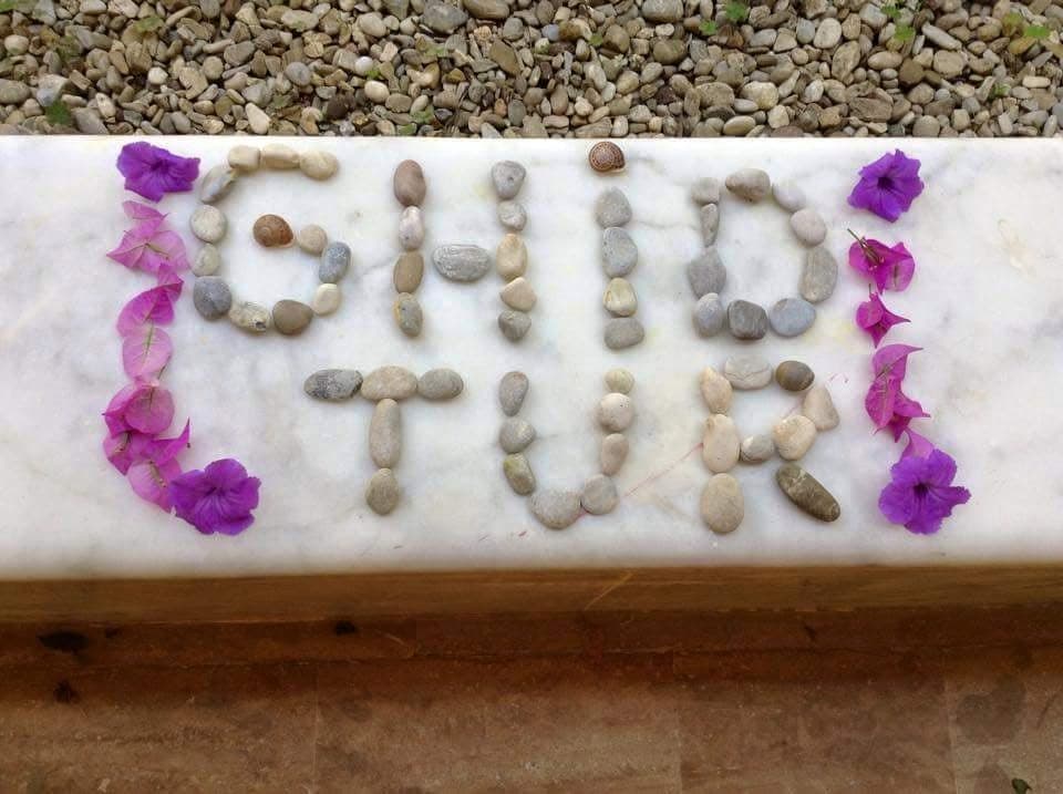 GhidTur scris din pietre, încadrat de flori violet.
